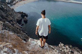 Man standing on a cliff and looking at water