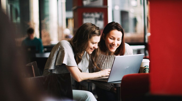 Young smiling students looking at laptop