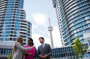 Three people talking in front on buildings and CN Tower