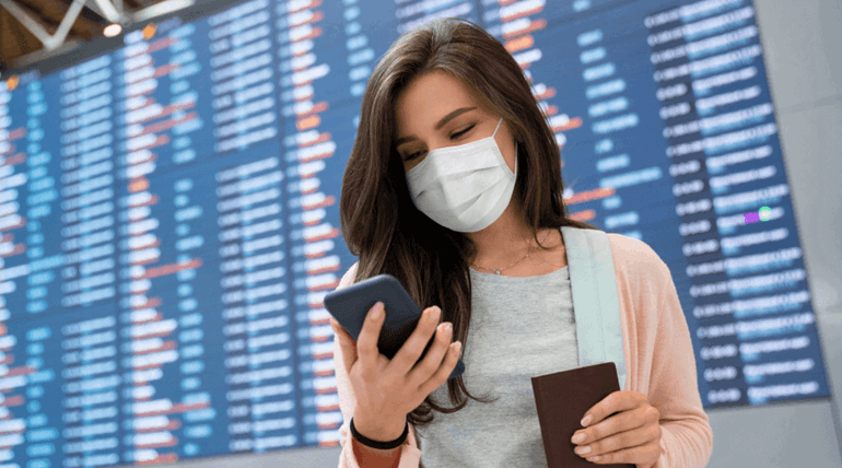 A young woman wearing a white mask and looking at her phone