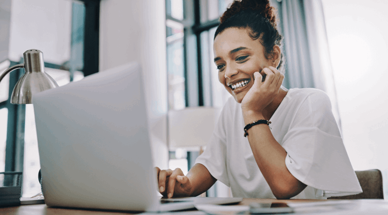 Woman looking and smiling at her laptop