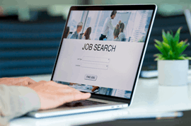 Hands typing job search on laptop