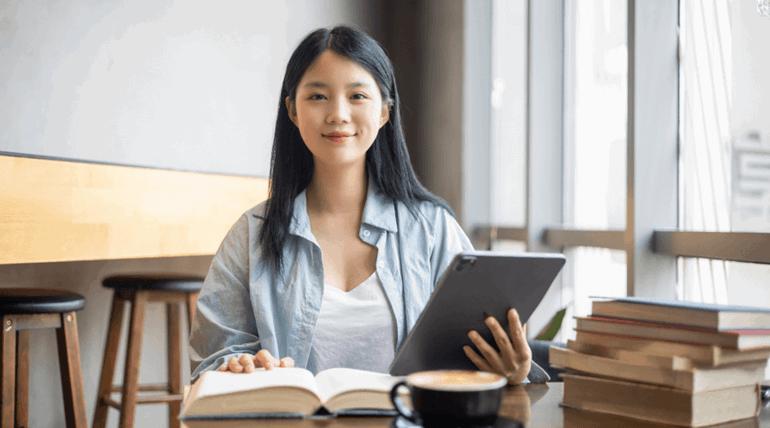 Woman looking at the camera and holding tablet in hand