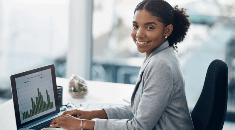 A woman smiling at the camera with charts on her laptop