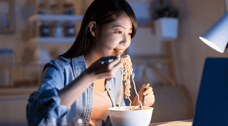 Girl enjoying her ramen noodle with chopsticks