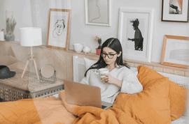 Woman holding cup and using laptop