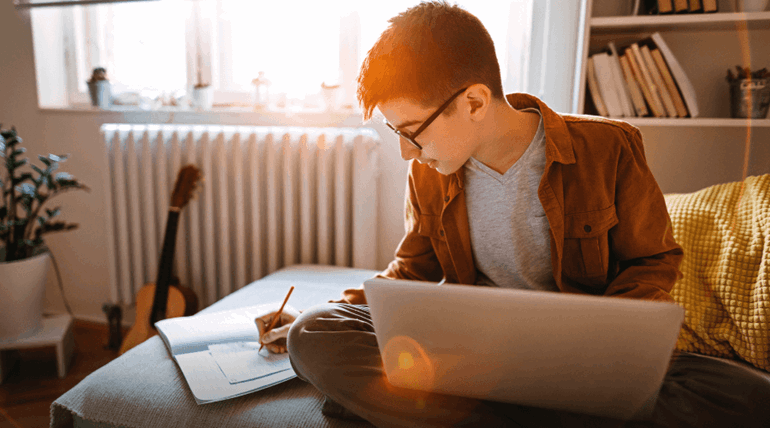 A young man, sitting alone at home taking notes