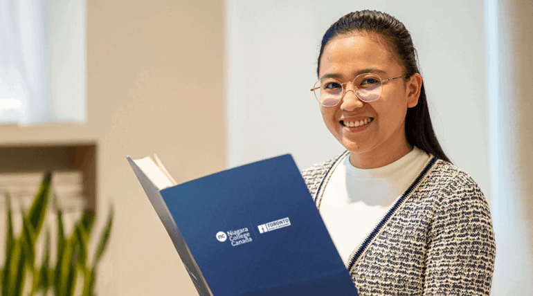 A young Asian woman was holding a document and smiling at the camera.