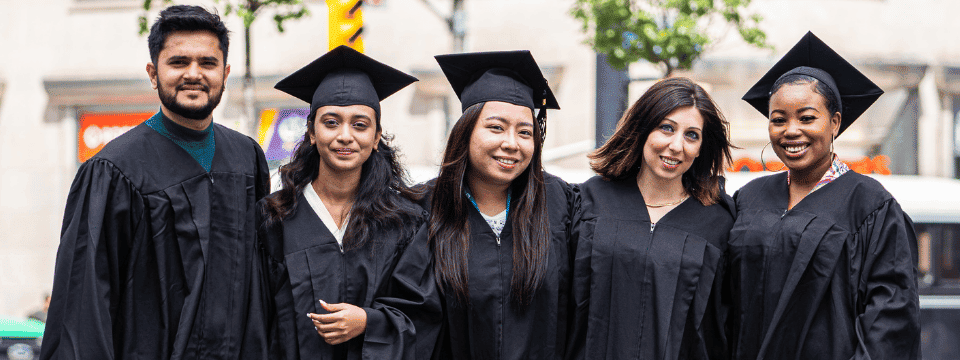 Group of graduates in caps and gowns standing outdoors